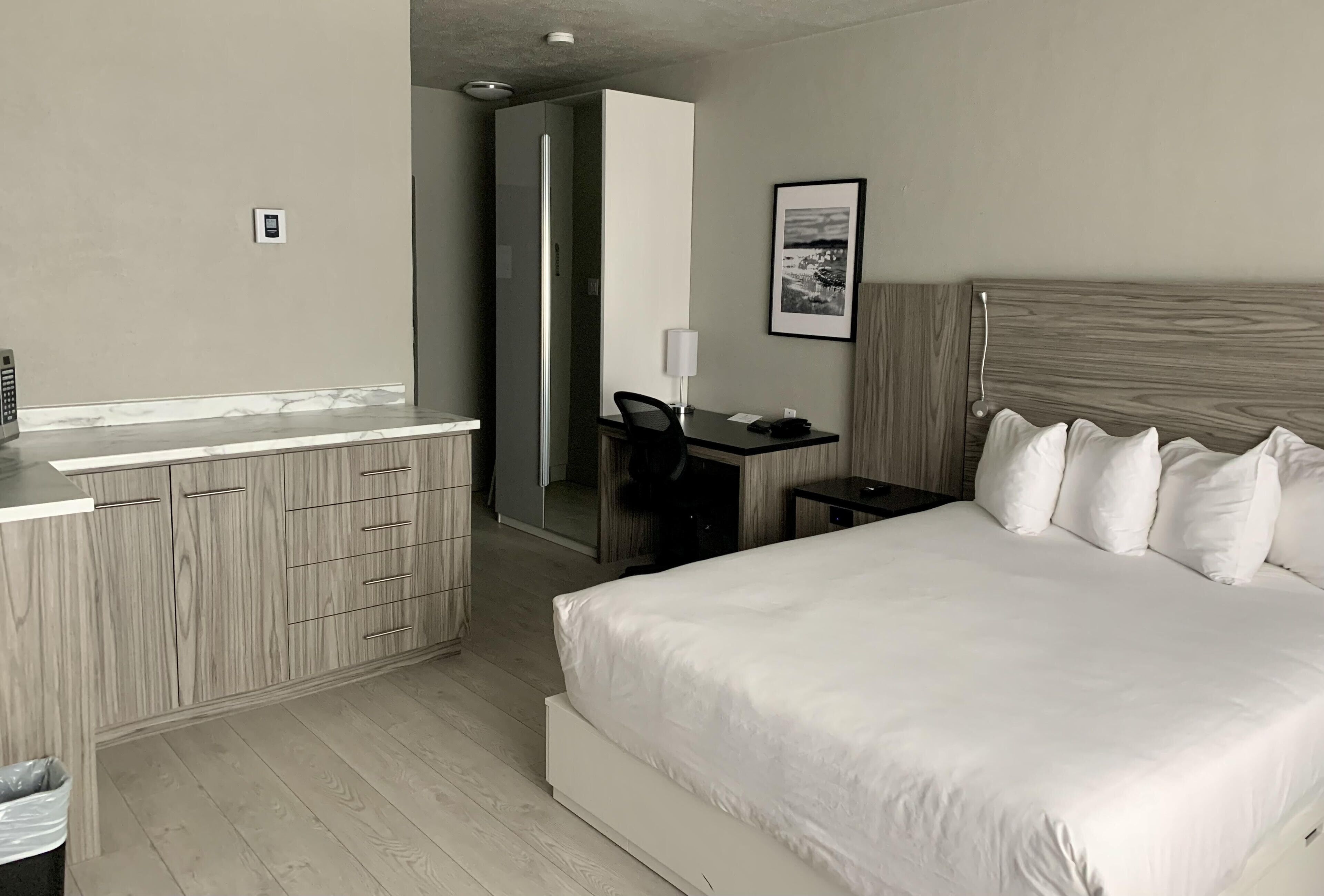 Ein Hotelzimmer mit Bett, Schreibtisch, Stuhl, Spiegel und kleinem Tisch.