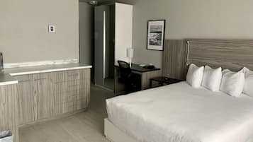 Ein Hotelzimmer mit Bett, Schreibtisch, Stuhl, Spiegel und kleinem Tisch.