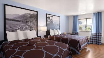 A hotel room with two beds, a large window with curtains, and artwork on the walls.