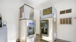A commercial kitchen with stainless steel appliances, including a refrigerator, an ice dispenser, and a washing machine.