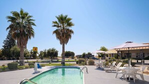 A pool area with a clear blue sky, palm trees, and outdoor seating.