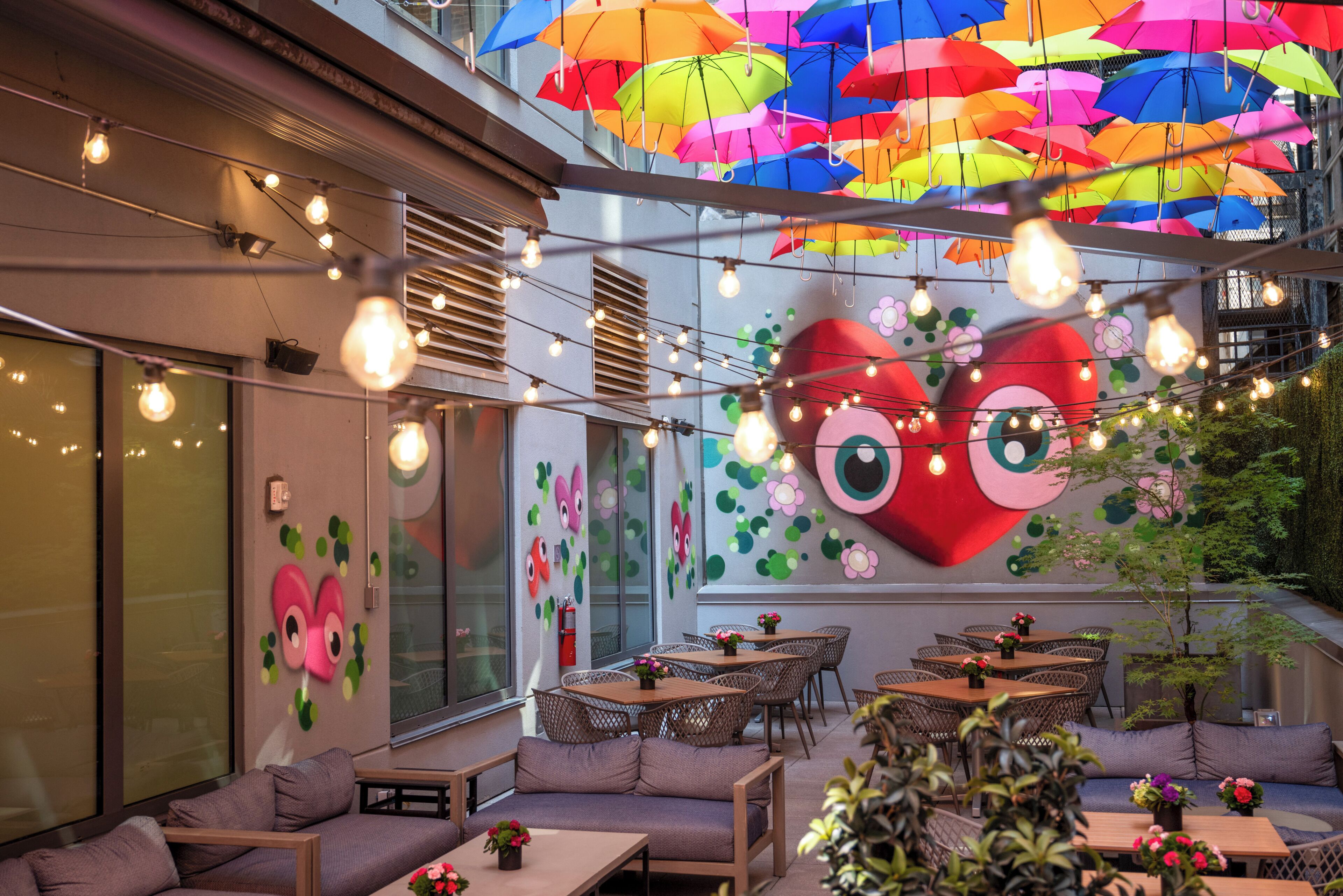 A restaurant with outdoor seating, string lights, and colorful umbrellas.