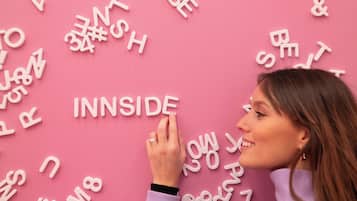 A person interacting with a pink wall covered in white letters and symbols.