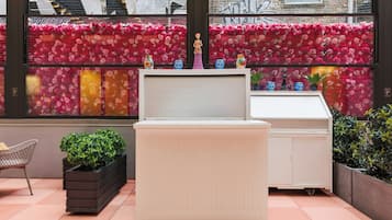 A room with a white cabinet, a small table, and a window with a floral wall.