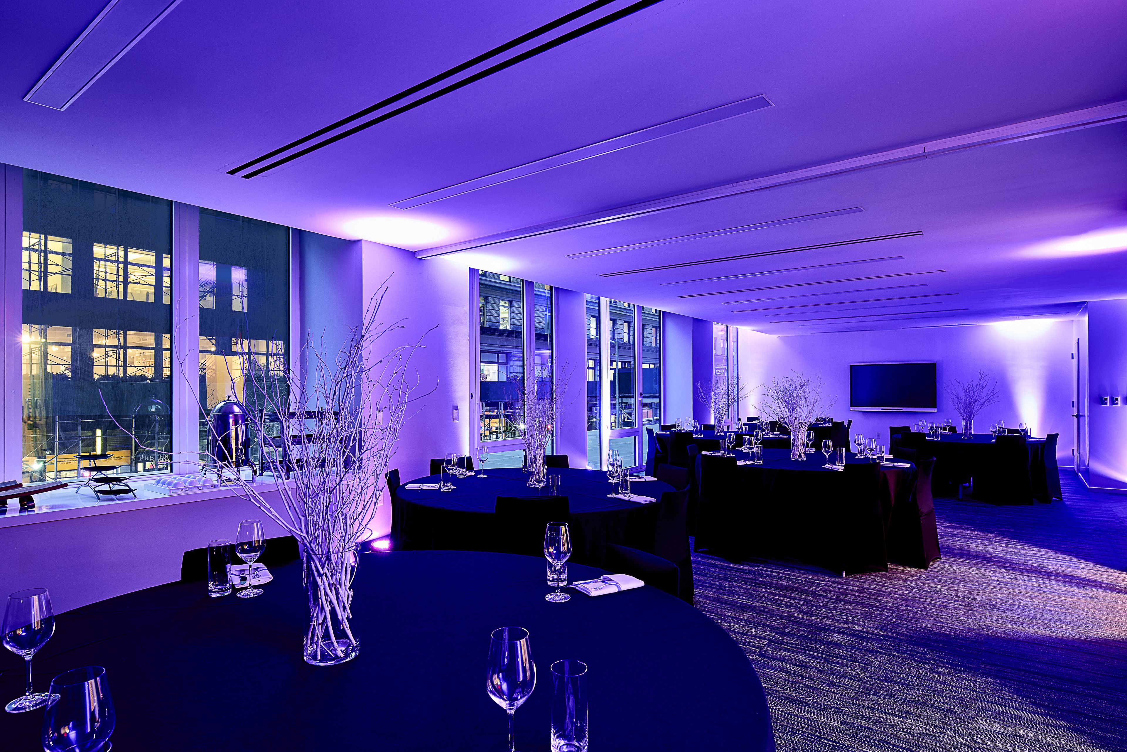 A conference room with round tables, chairs, and a large window with a view of buildings.
