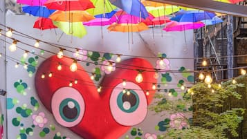 A restaurant with outdoor seating, colorful umbrellas, and a large heart-shaped mural.