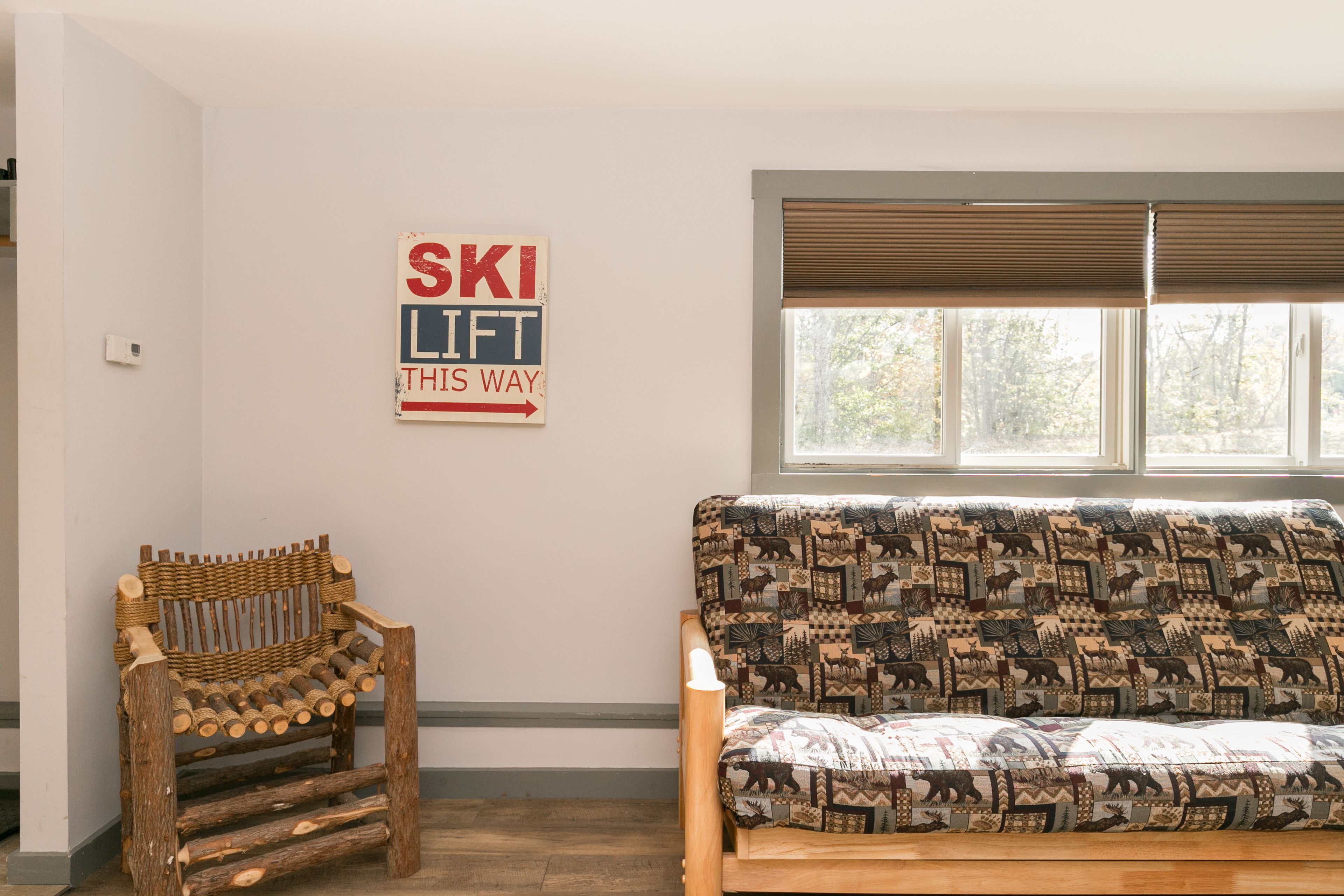 Et værelse med en træbænk, en stribet sofa og et skilt på væggen, der står "SKI LIFT DENNE VEJ".