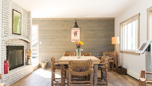 Un comedor rústico con chimenea de ladrillo, mesa de madera y sillas de mimbre.