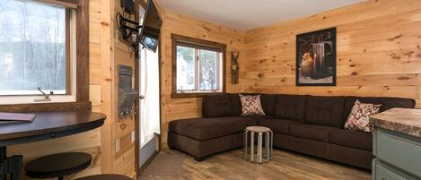 A wooden interior with a sofa, a small round table, and a bench.