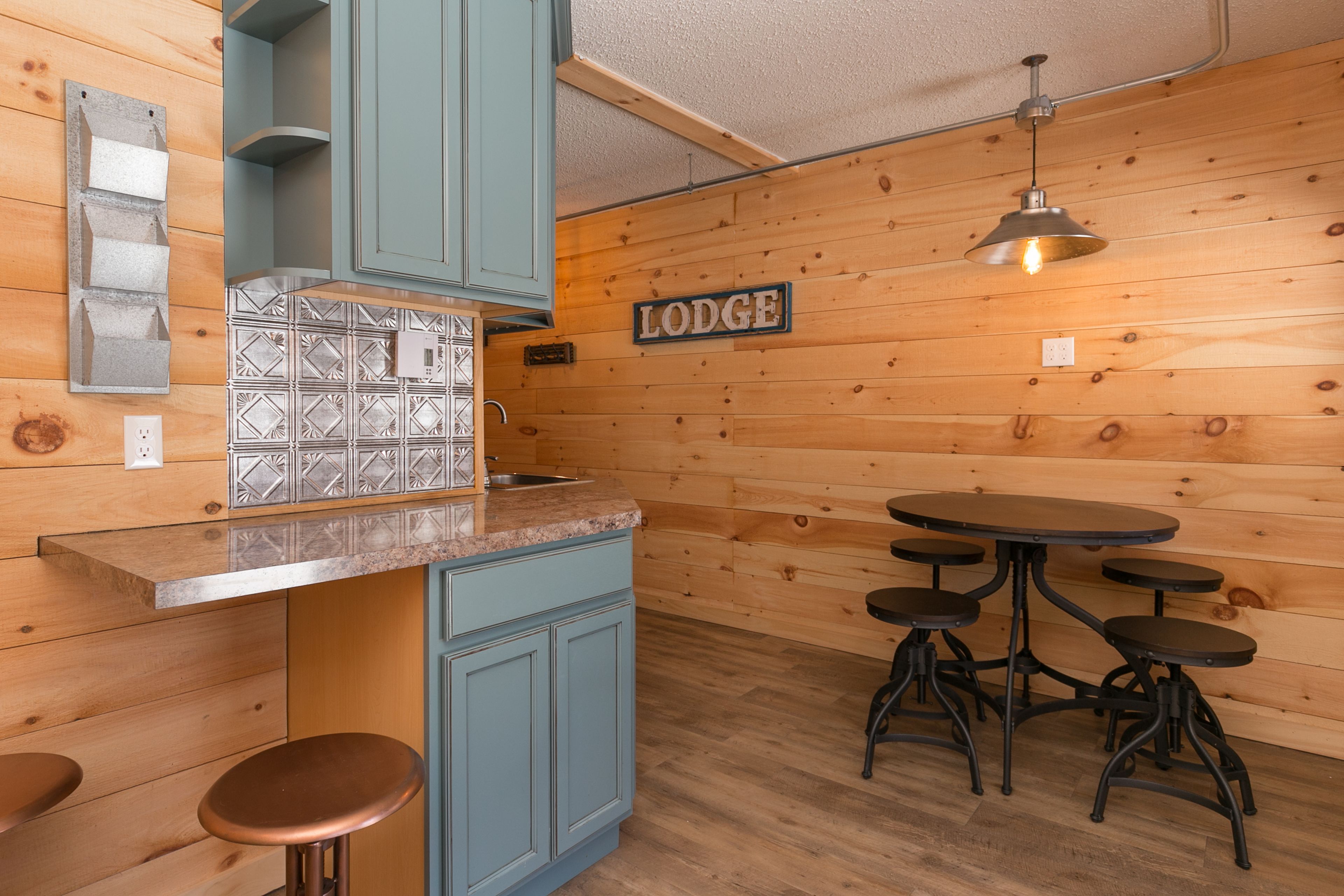 A cozy lodge kitchen with wooden walls, a tiled backsplash, and a 'Lodge' sign.