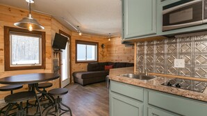 Una cocina compacta con comedor, paredes de madera y microondas integrado.