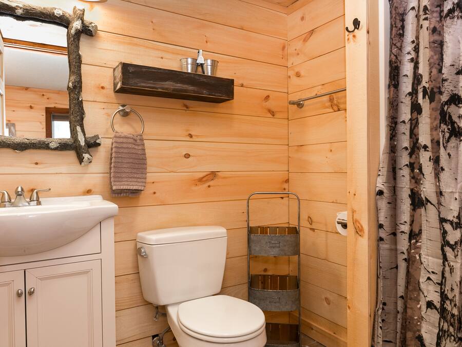 Een houten badkamer met een wit wastafel, toilet en een spiegel met een rustieke lijst.