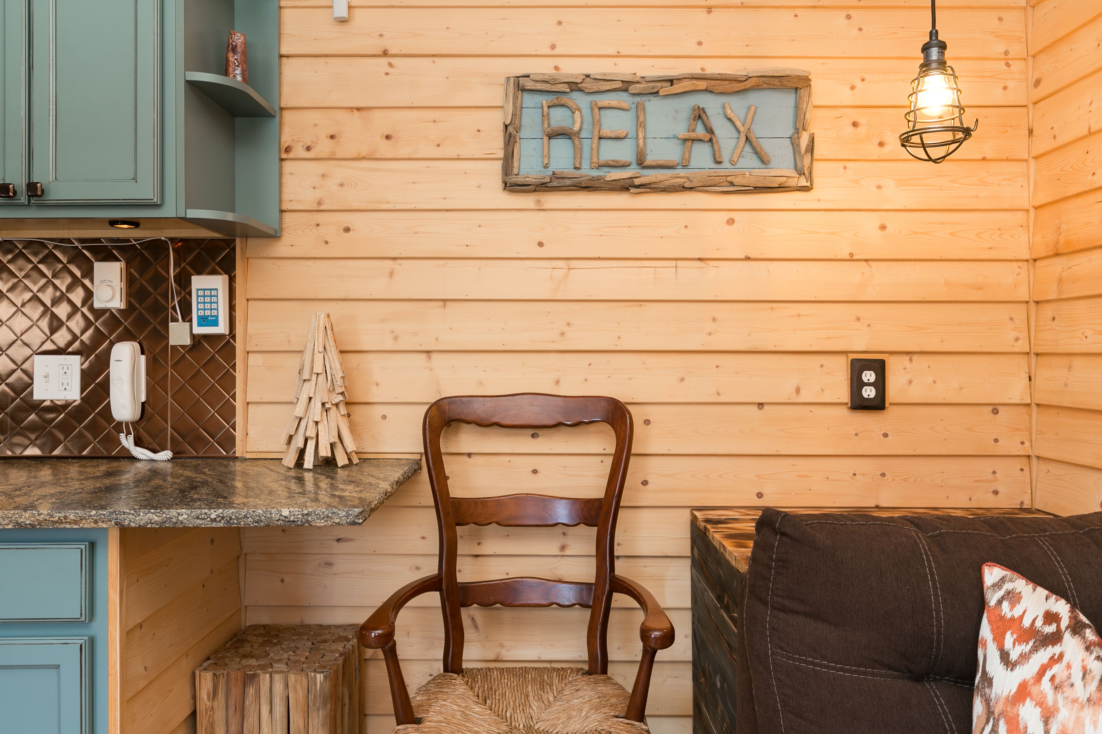 A wooden interior with a wooden chair, a sign that says "RELAX", a wooden bench, and a small wooden stool.