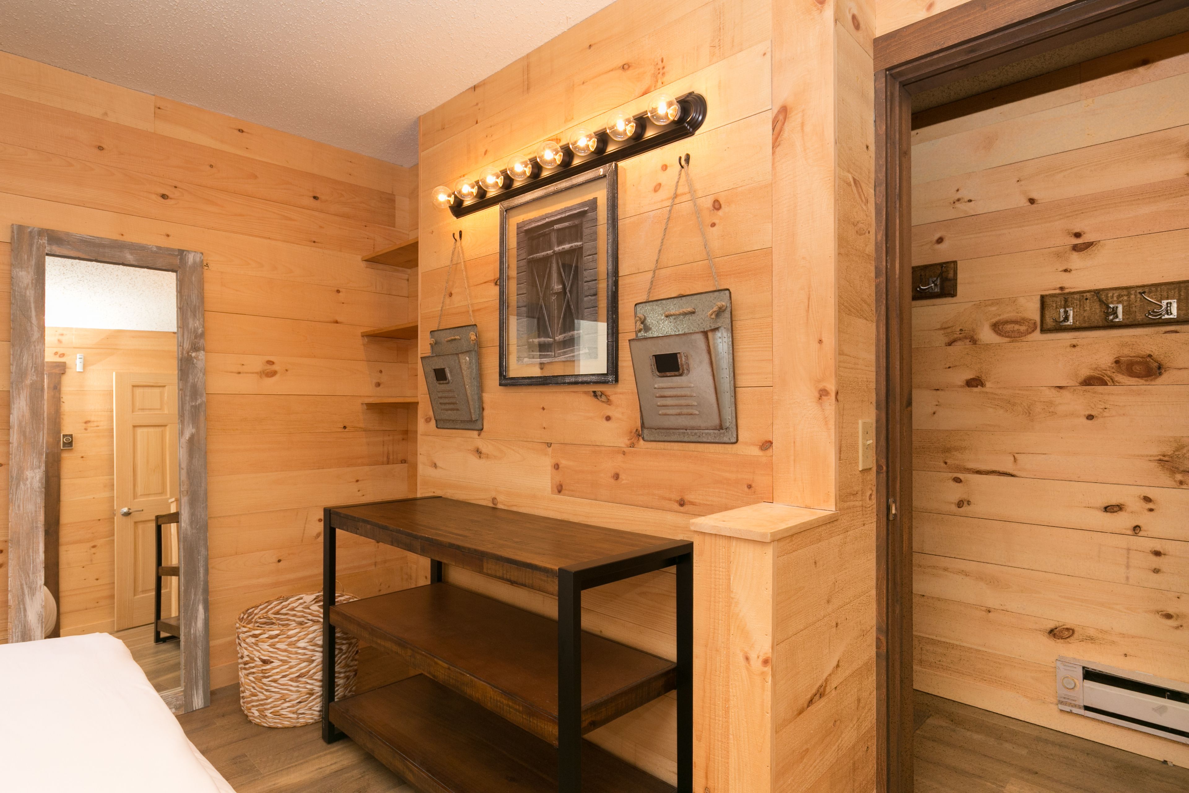 A wooden interior with a bed, a table, and a wall-mounted light fixture.