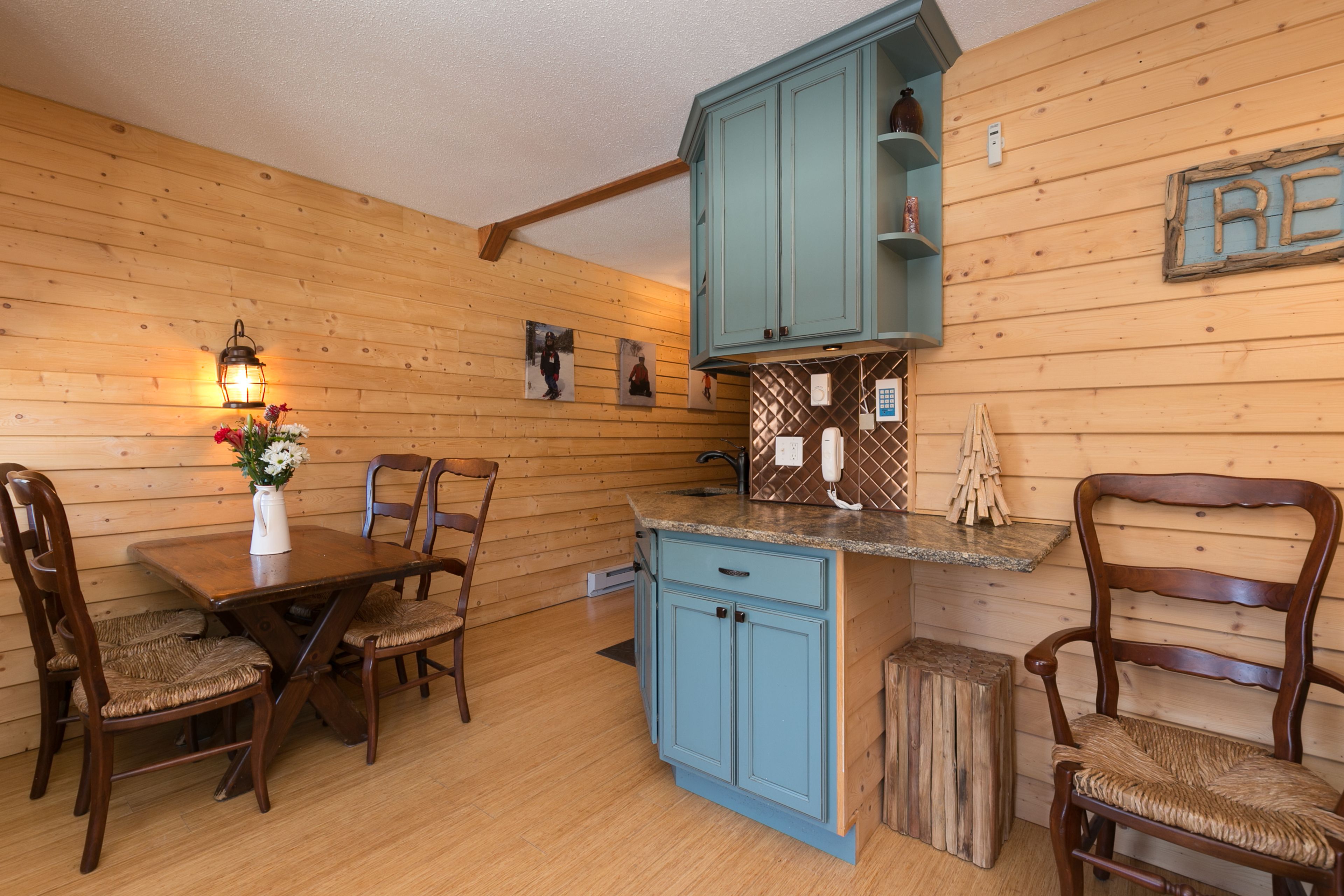 A wooden-paneled room with a dining table, chairs, a blue kitchen island, and wooden cabinets.