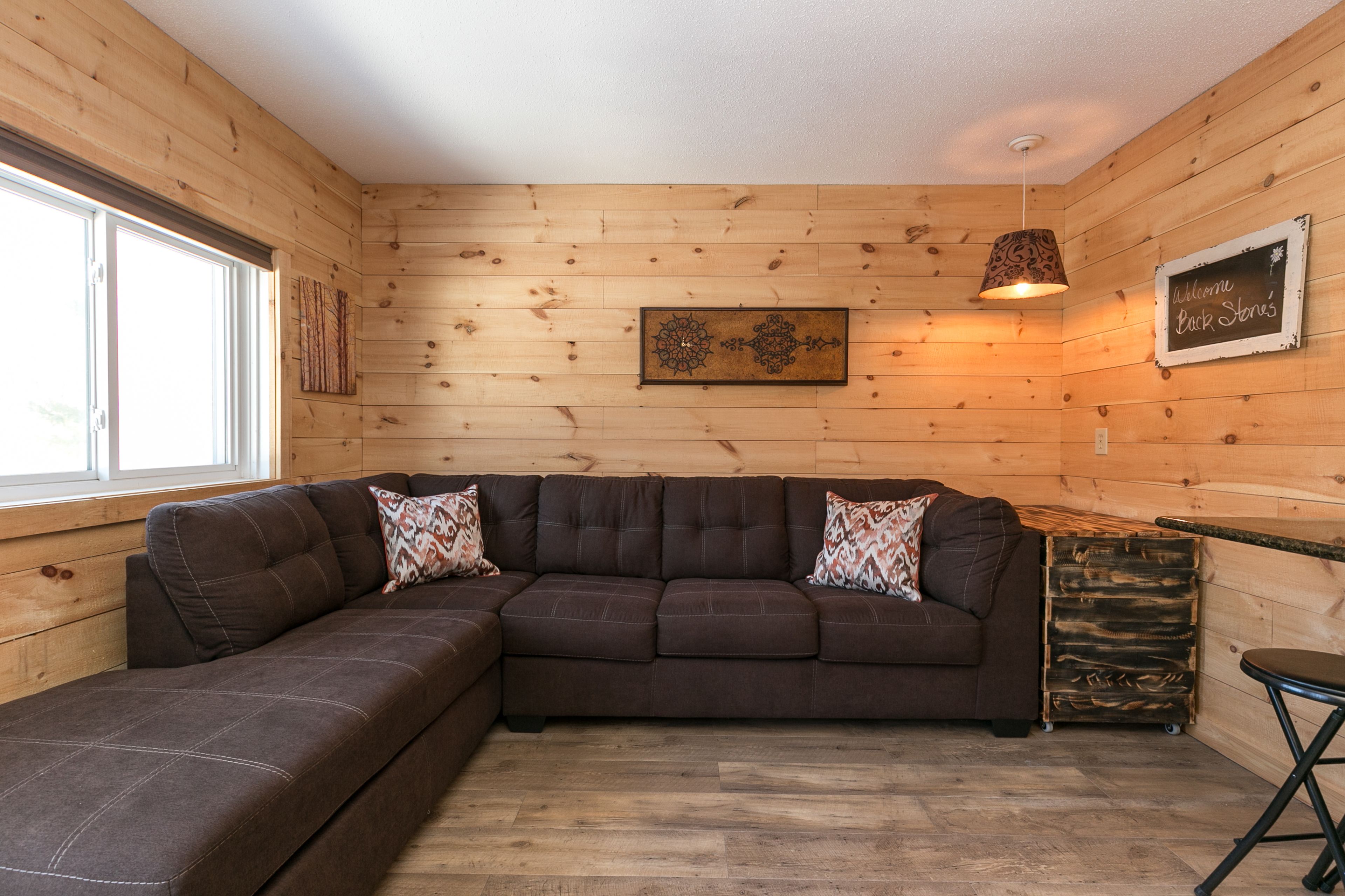 A wooden interior with a sectional sofa, a small table, and a decorative wall piece.