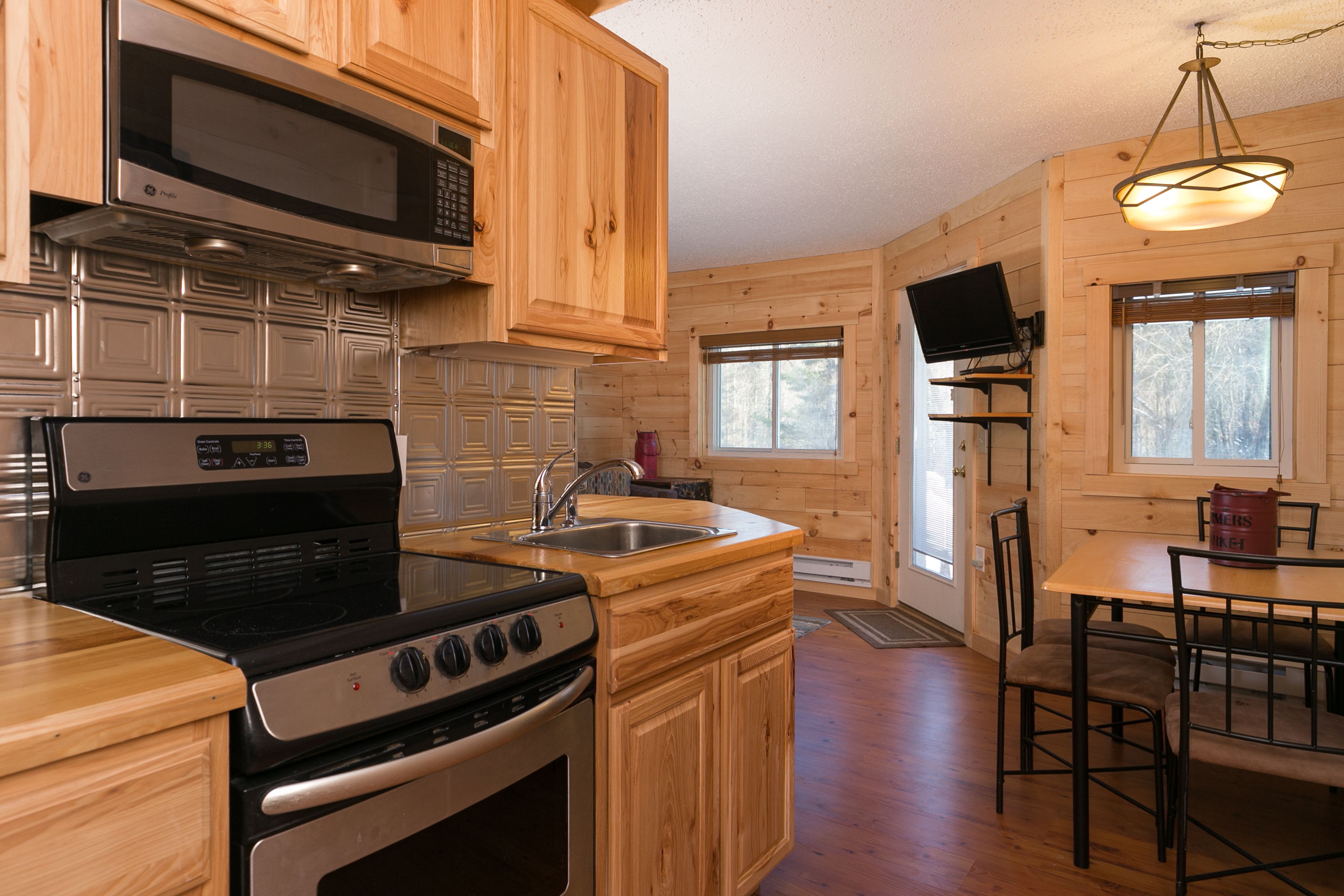 A kitchen with wooden cabinets, a microwave, a stove, and a sink.