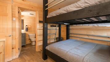 A bunk bed room with wooden walls, a toilet, and a small window.