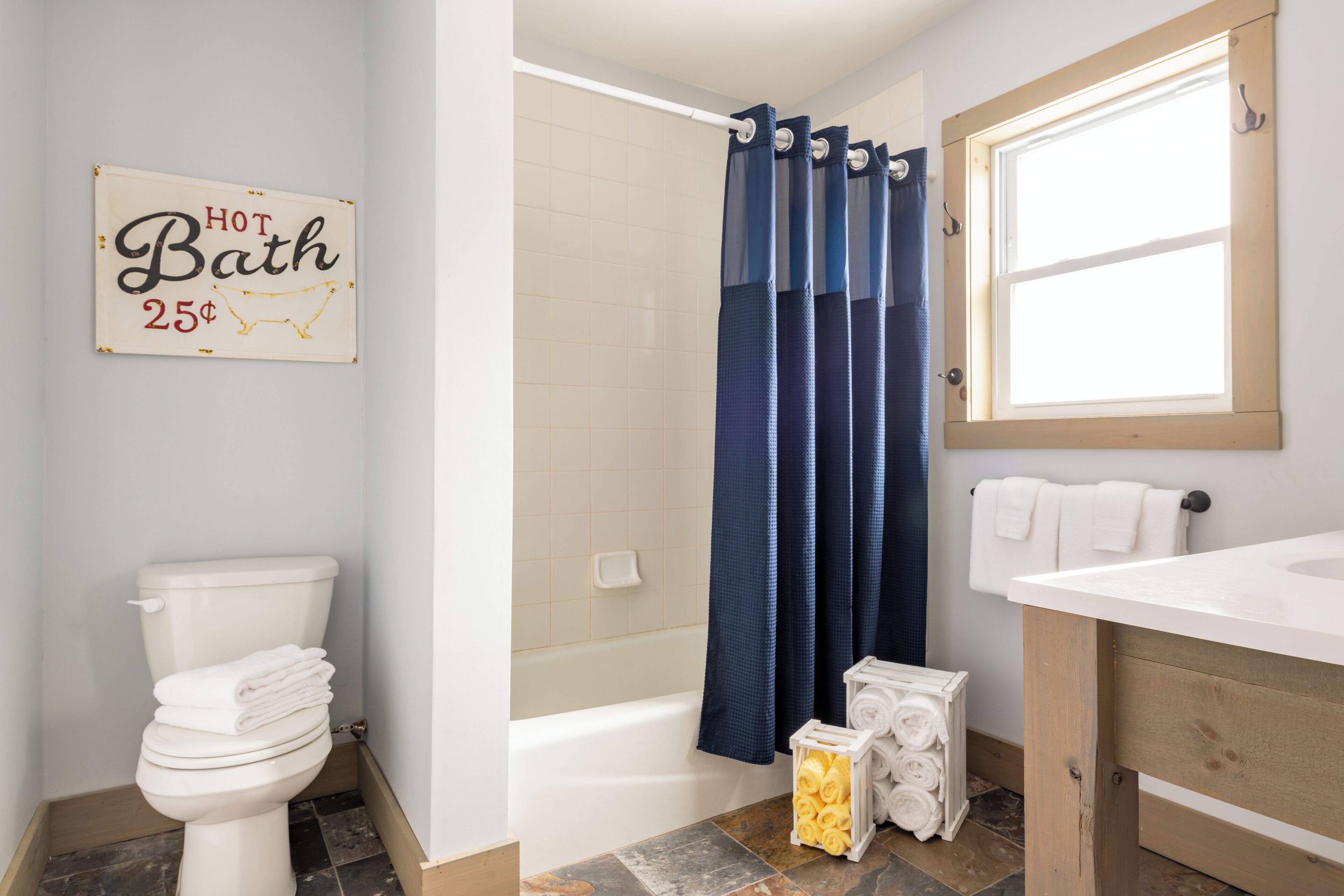 Un baño con inodoro, bañera, cortina de ducha y un cartel que dice 'Baño CALIENTE 25¢'.