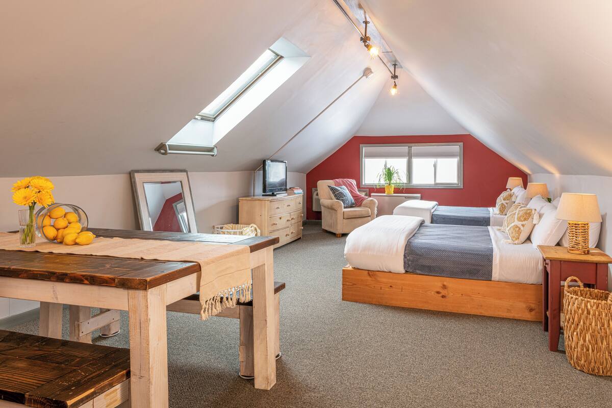 Um quarto de sótão acolhedor, com teto inclinado, uma cama de madeira, uma escrivaninha e uma cadeira.