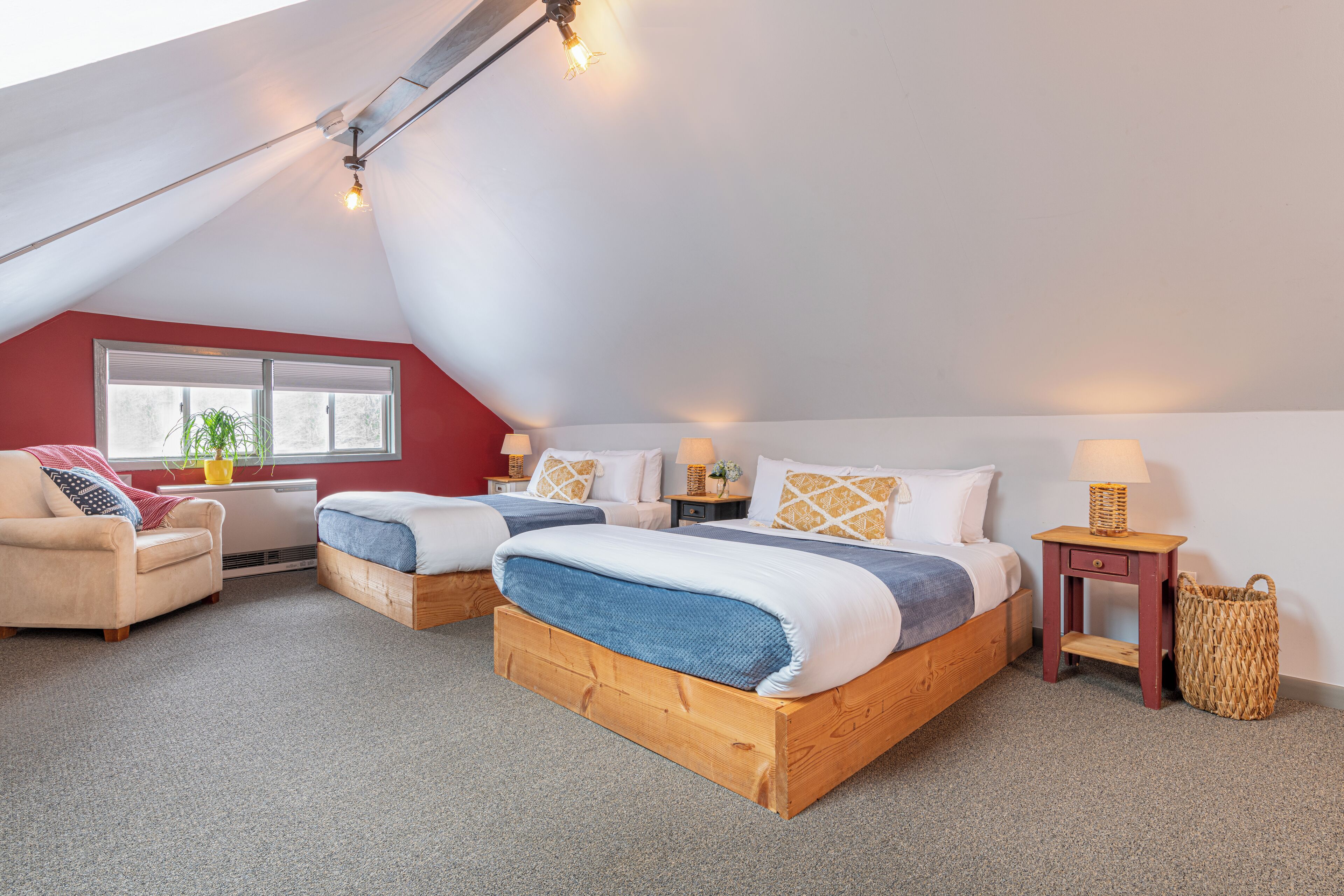 Une chambre avec deux lits, un canapé, une fenêtre et une lampe.