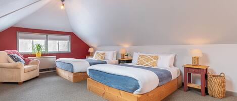 Une chambre avec deux lits, un canapé, une fenêtre et une lampe.