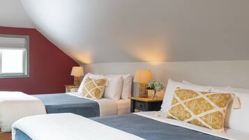 Une chambre avec deux lits, une fenêtre et deux tables de chevet ornées de lampes et d’objets décoratifs.
