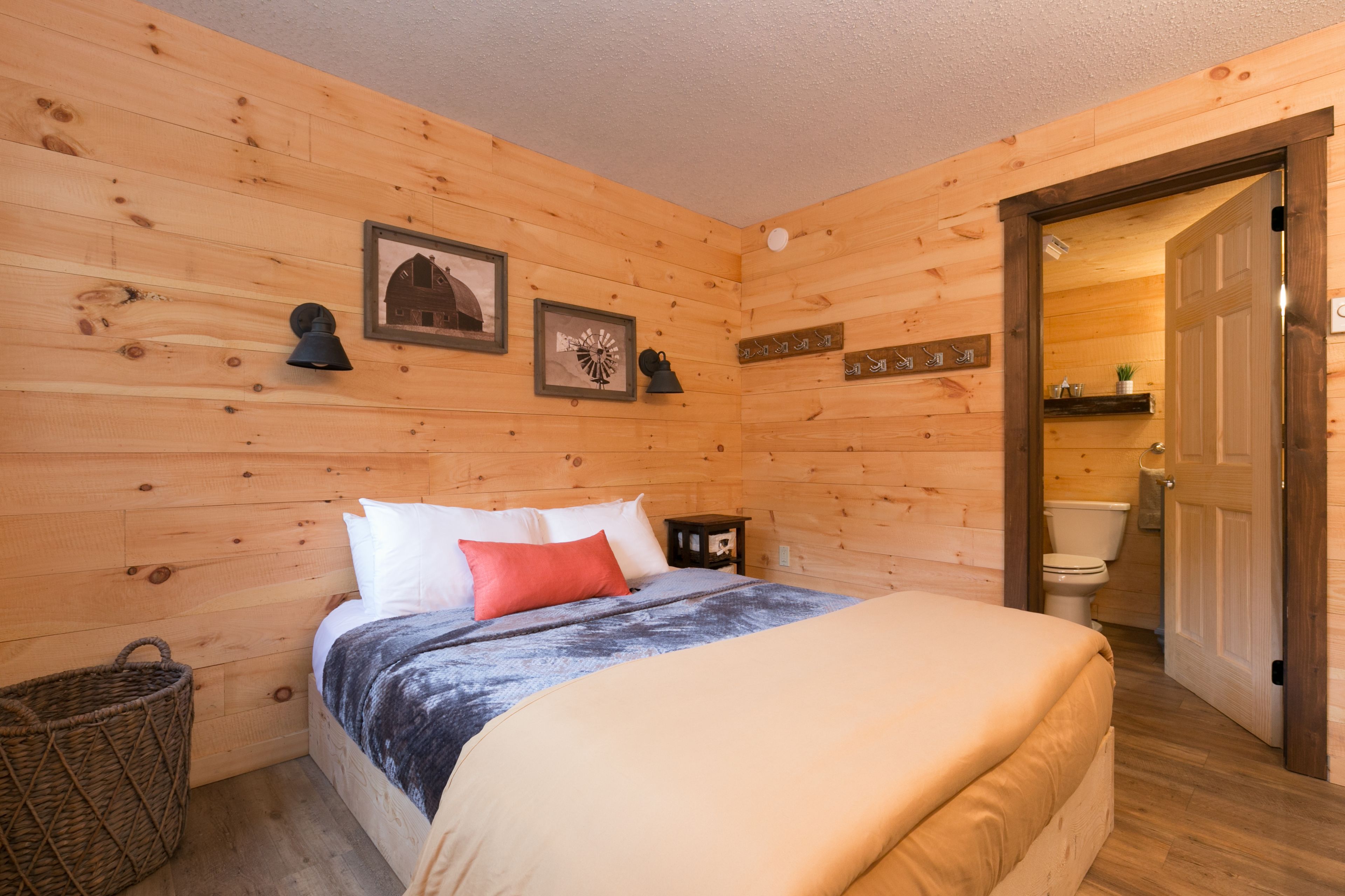 Ein Zimmer mit Holzwänden, einem Bett, einem kleinen Nachttisch und einem Korb.