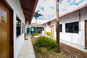 Un pasillo con piso de baldosas, una palmera y una puerta con el número 27.