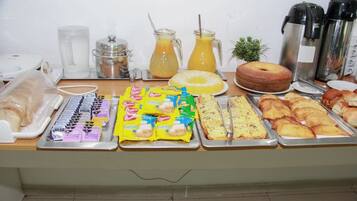 Una mesa de buffet con diversos alimentos, como pasteles, sándwiches y salsas.
