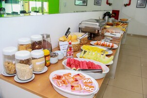 Un bufé con diversos alimentos, incluyendo frutas, cereales y salsas.