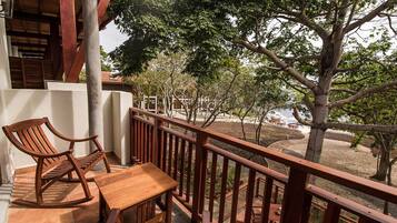 Une terrasse en bois avec une table et des chaises, donnant sur un espace aménagé avec des arbres et offrant une vue sur un bâtiment en arrière-plan.