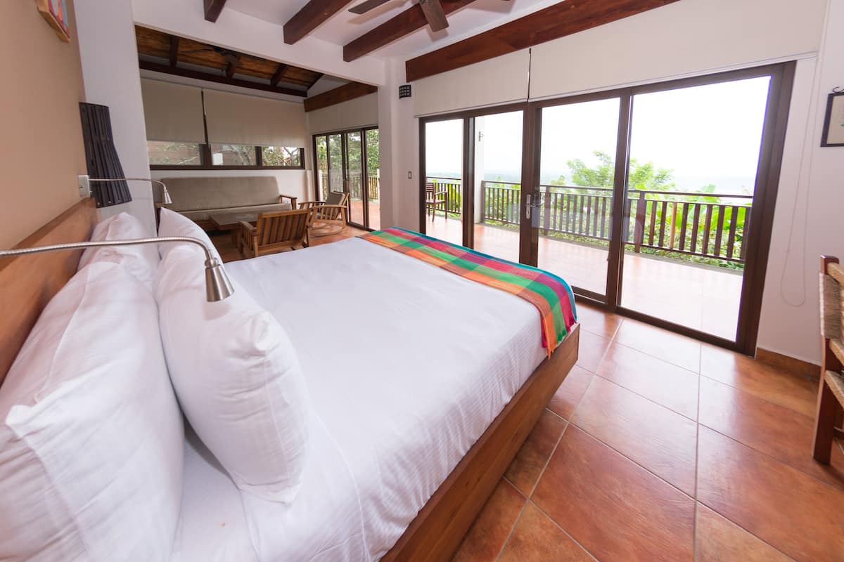 Ein Schlafzimmer mit einem großen Bett, einem Balkon mit Blick und einer kleinen Küchenzeile.