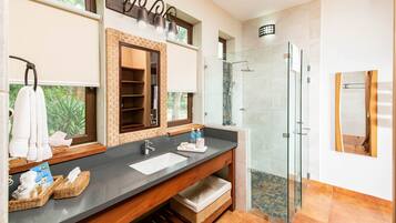 A modern bathroom with a large vanity, a glass shower enclosure, and a large mirror.