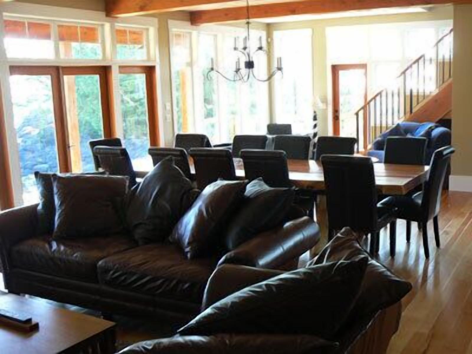 Amplia sala de estar con sofá de cuero, mesa de comedor y sillas.