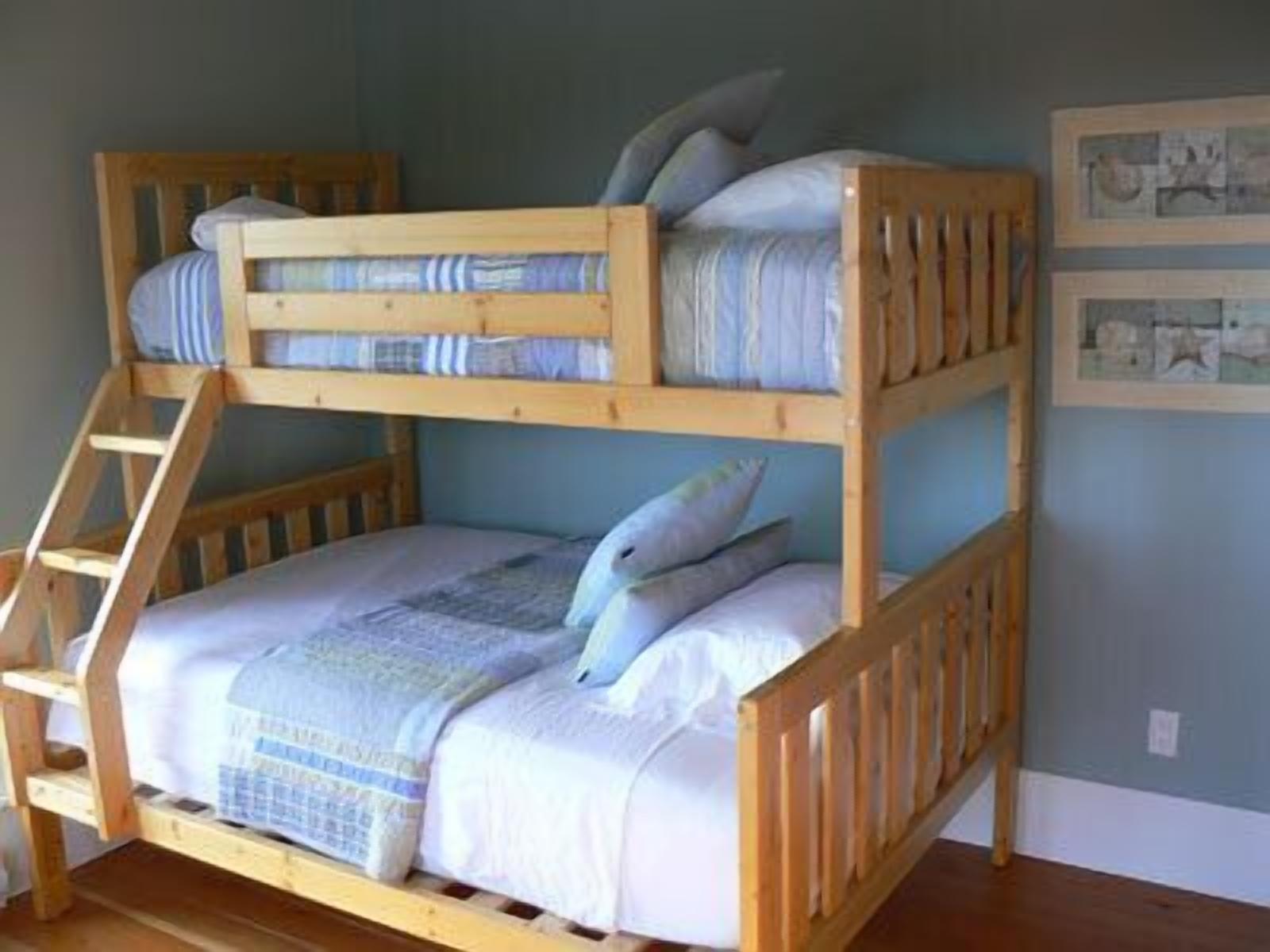 A bunk bed with a ladder, blue bedding, and pillows.