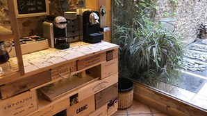 A coffee station with espresso machines, a chalkboard menu, and wooden crates labeled with wine names. - Hotel Boutique Niu Del Sol (Palau-Saverdera)