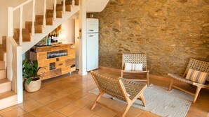 A cozy living area with a stone wall, wooden staircase, and a seating area with two chairs and a small table. - Hotel Boutique Niu Del Sol (Palau-Saverdera)