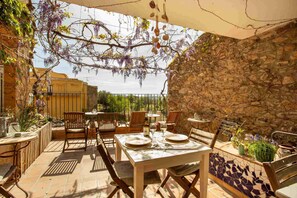 An outdoor patio with stone walls, wooden furniture, and hanging plants. - Hotel Boutique Niu Del Sol (Palau-Saverdera)