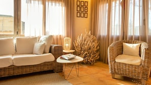 A cozy living room with a sofa, a chair, a small table, and a decorative plant. - Hotel Boutique Niu Del Sol (Palau-Saverdera)