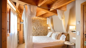 A bedroom with a stone wall, a canopy bed, and a small bedside table. - Hotel Boutique Niu Del Sol (Palau-Saverdera)