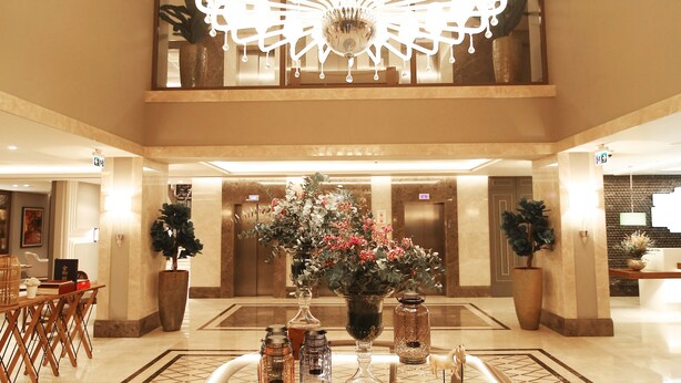 Un hall d’entrée spacieux, agrémenté d’un grand lustre, d’une table ronde décorée et de plantes en pot.