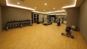 Une salle de sport spacieuse équipée de divers appareils d’exercice, notamment des tapis de course, des poids et un rameur.