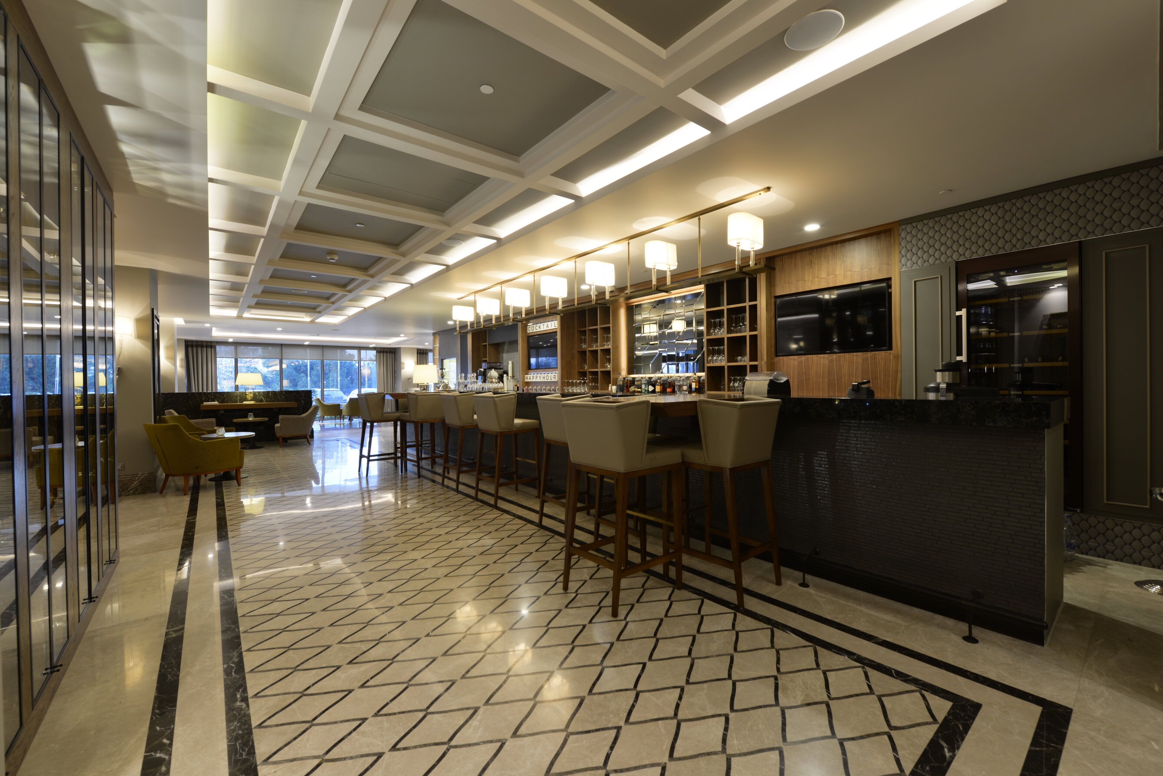 Um espaço de bar moderno com pé direito alto, iluminação embutida e balcão com banquetas.