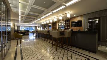 Um espaço de bar moderno com pé direito alto, iluminação embutida e balcão com banquetas.