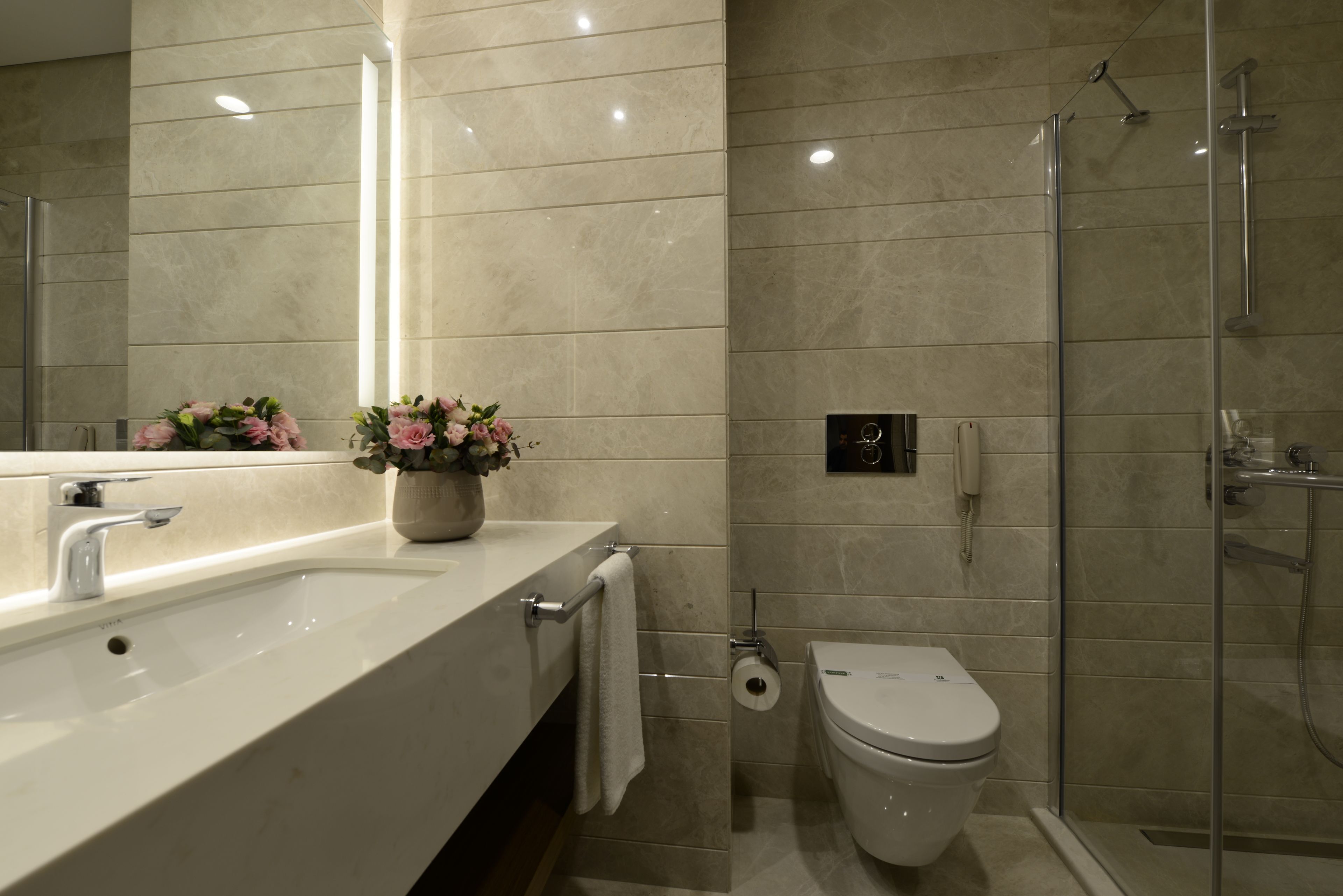 Un baño moderno con un lavamanos grande, un inodoro y una cabina de ducha de vidrio.