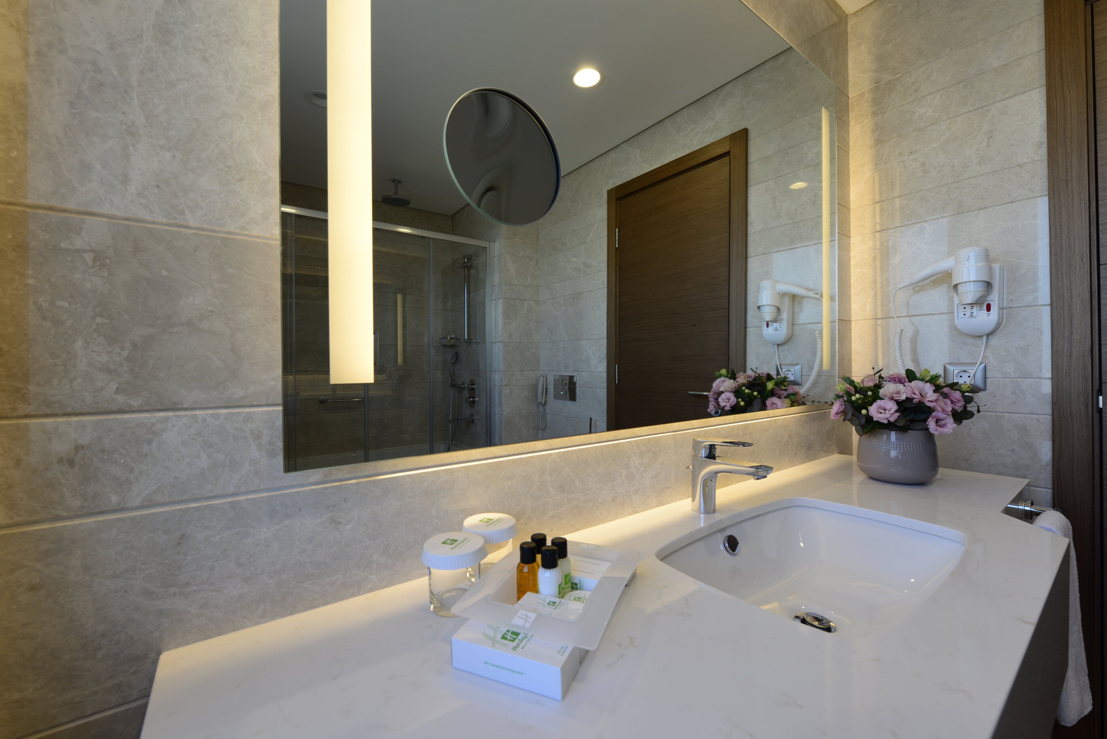 A modern bathroom with a large mirror, a dual sink vanity, and a shower enclosure.