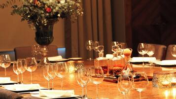A dining table set with multiple wine glasses, plates, and cutlery, with a vase of flowers in the background.