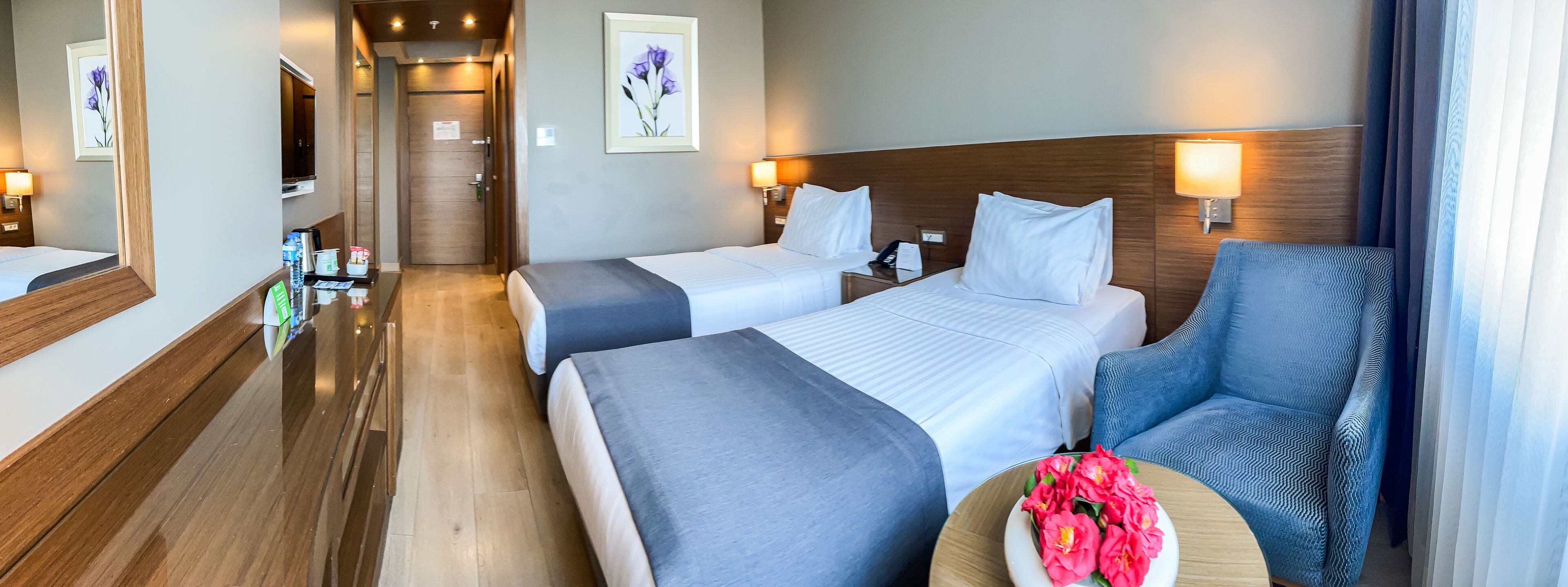 A hotel room with two beds, a seating area, and a bathroom.