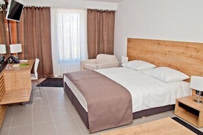 A hotel room with a large bed, a desk with a chair, a TV mounted on the wall, and a window with curtains. - Hotel Residence AC SAN Marino (Lopar)